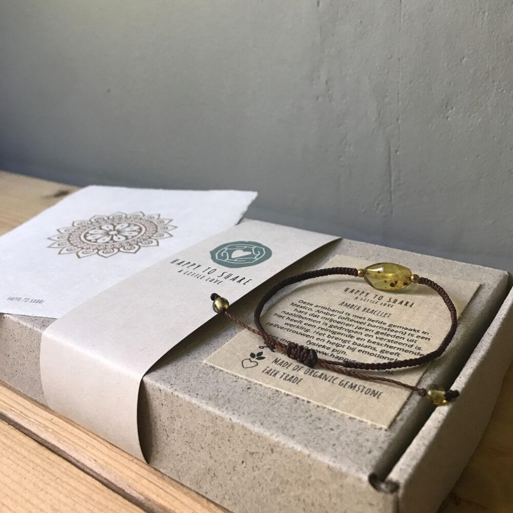 Een bijzonder cadeau bestaande uit een bruine amber bracelet (barnsteen armband) op een doosje van graskarton met een mandala zonnebloem kaart van handgeschept papier.