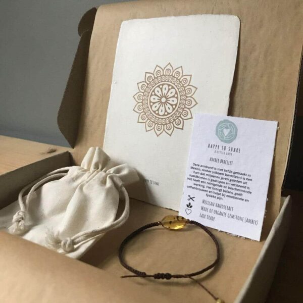 Een bijzonder cadeau bestaande uit een bruine amber bracelet (barnsteen armband) in een doosje van graskarton met een biologisch katoenen zakje en mandala zonnebloem kaart van handgeschept papier.