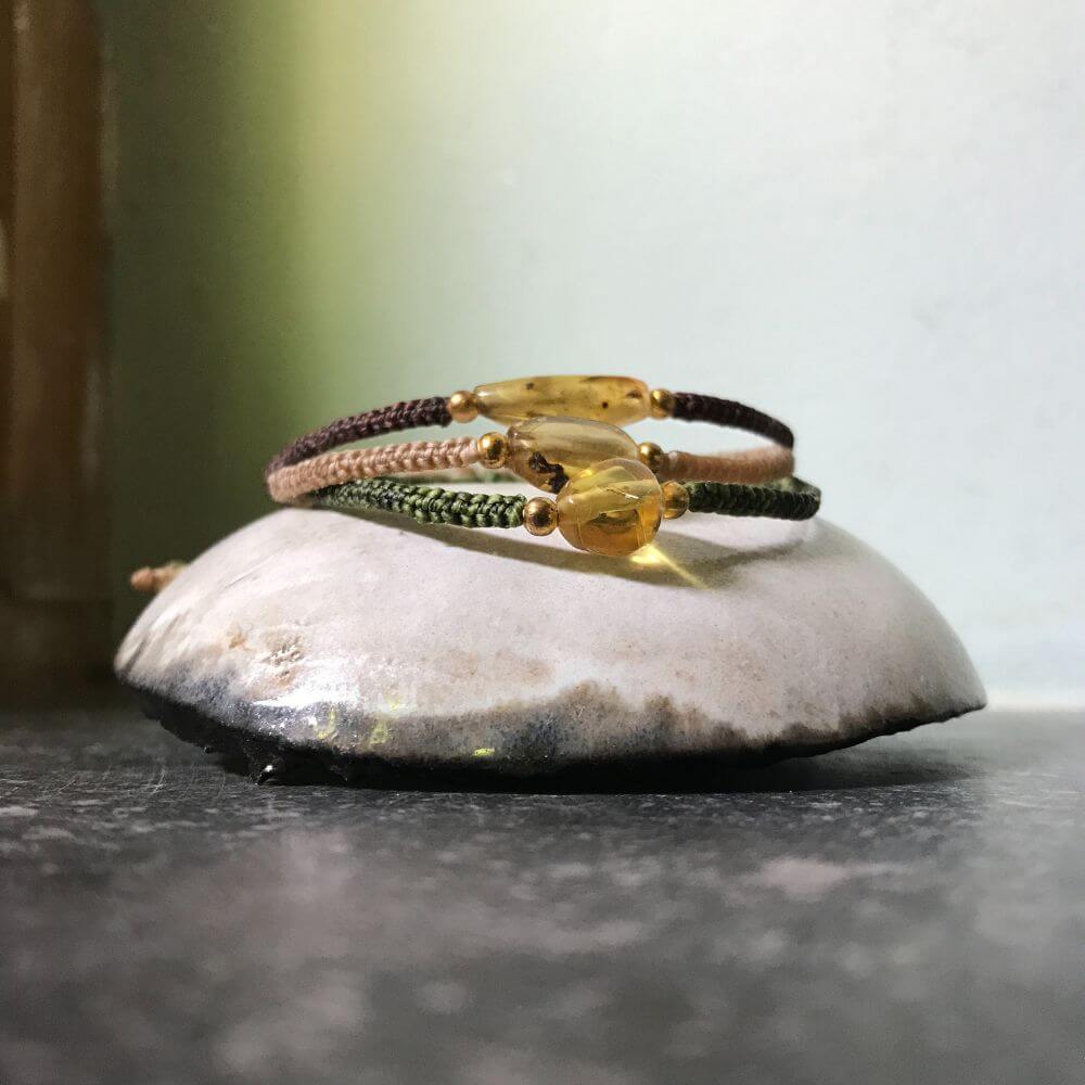 Amber bracelet (barnsteen armband) in bruin, ecru en groen op een schoteltje van keramiek.