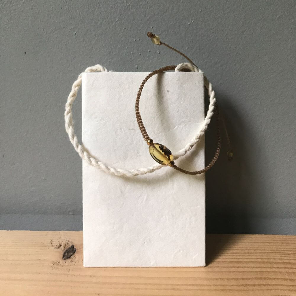Ecru kleurige amber bracelet (barnsteen armband) met wit zakje van handgeschept papier.