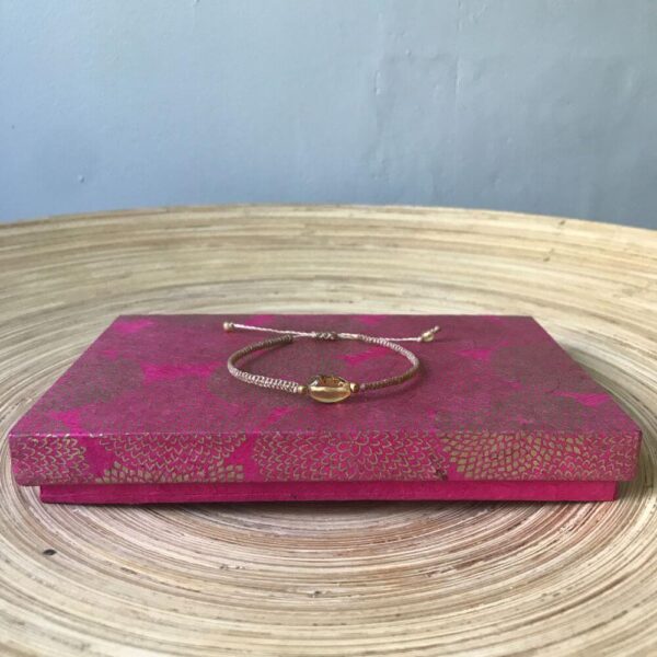 Ecru kleurige amber bracelet (barnsteen armband) met goud roze sieradendoosje van handgeschept papier.