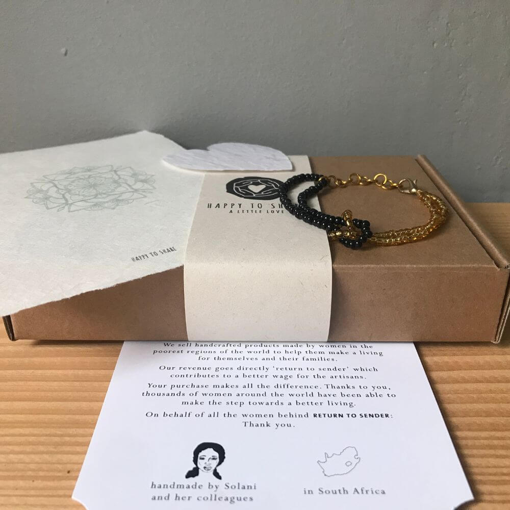 Een bijzonder cadeau met een zwart en goud kleurige infinity armband op een doosje van kraftkarton met een mandala kaart van handgeschept papier. en een wit hartje van groeipapier.