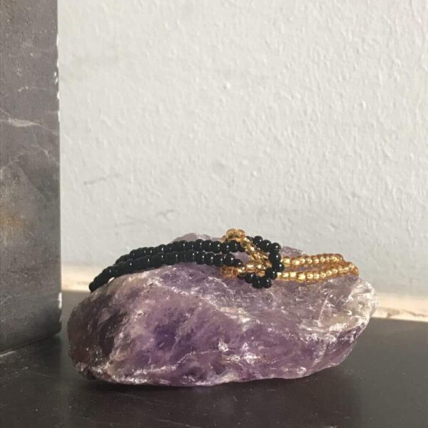 Zwart en goud kleurige infinity armband op een amethist edelsteen.