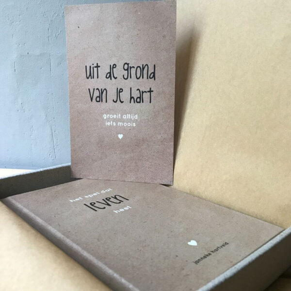 Lichtbruin boek het spel dat leven heet met een bijpassende kaart en een doosje van graskarton met kraft bruin zijdepapier.