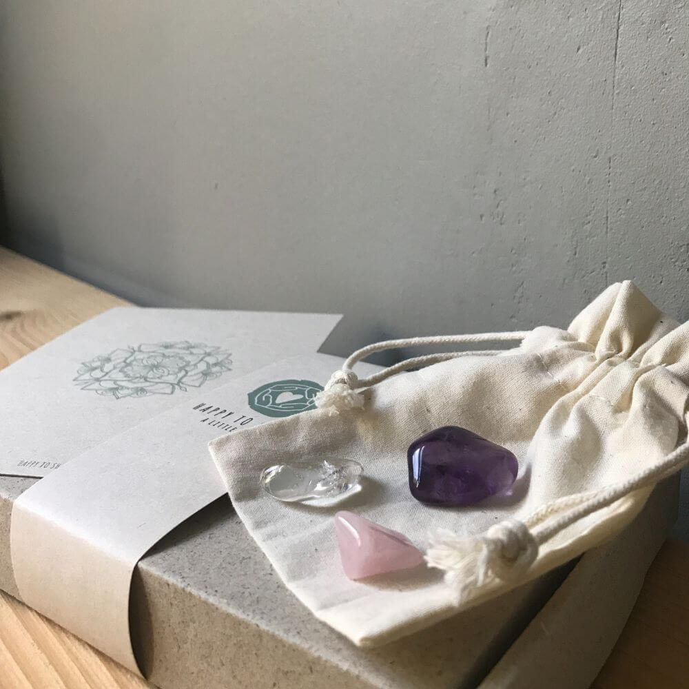 Ecru buidelzakje met amethist, bergkristal en rozenkwarts edelstenen en mandala kaart op cadeau doosje van graskarton.