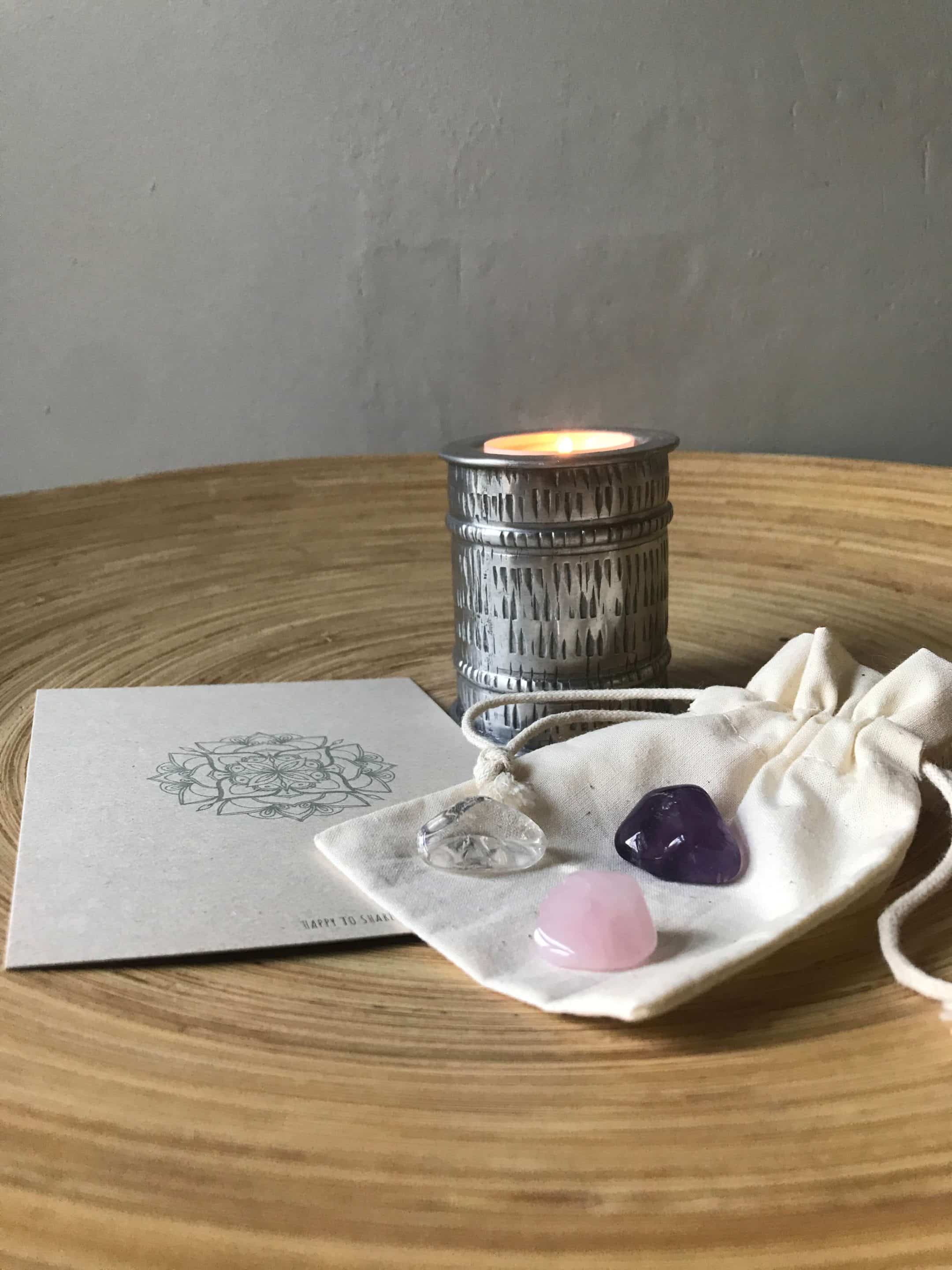 Ecru buidelzakje met amethist, bergkristal en rozenkwarts edelstenen, mandala kaart en brandend kaarsje in aluminium kaarsenhouder.