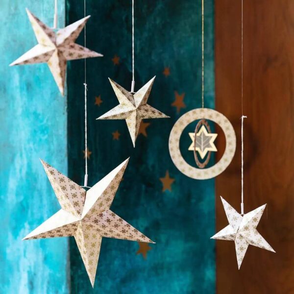 Hangende ecru kleurige raamhanger met twee ringen en een ster, grote kerstster en kleine kerststerren van handgeschept papier.