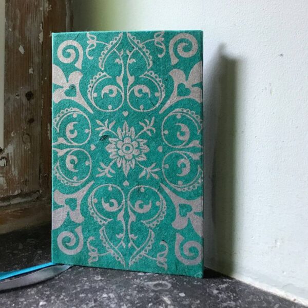 Groen notitieboekje met zilveren bloemversiering en twee leeslinten.