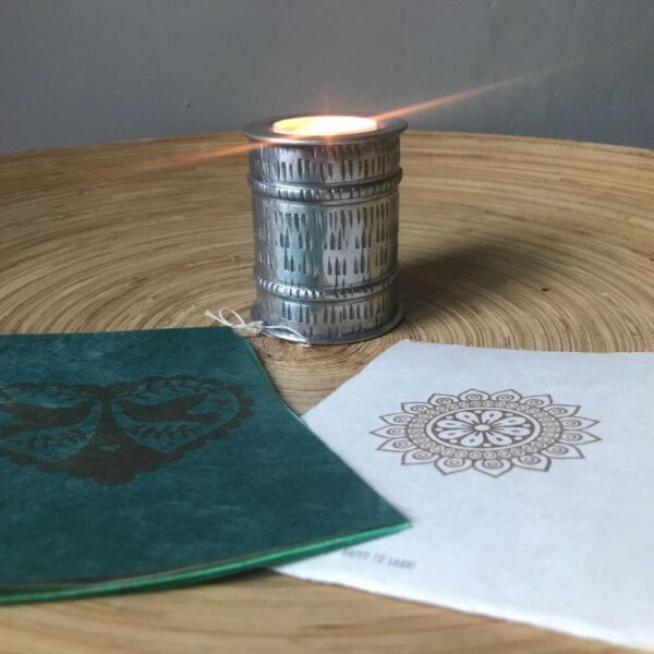 Vredesduiven op groen handgeschept papier, een mandala kaart met scheprand en een brandend theelichtje in aluminium kaarsenhouder.
