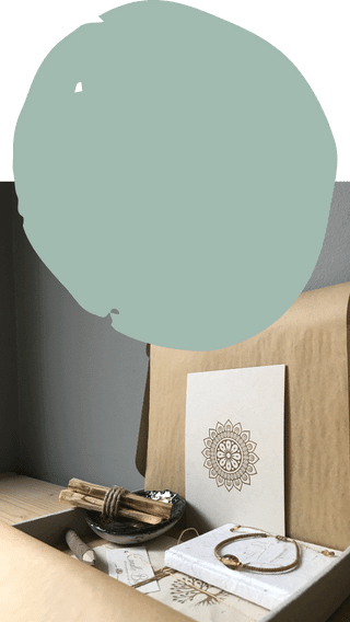 Geschenkbox van graskarton met keramieken schoteltje met palo santo, barnsteen armband, lichtzakjes, notitieboekje en mandala kaart.
