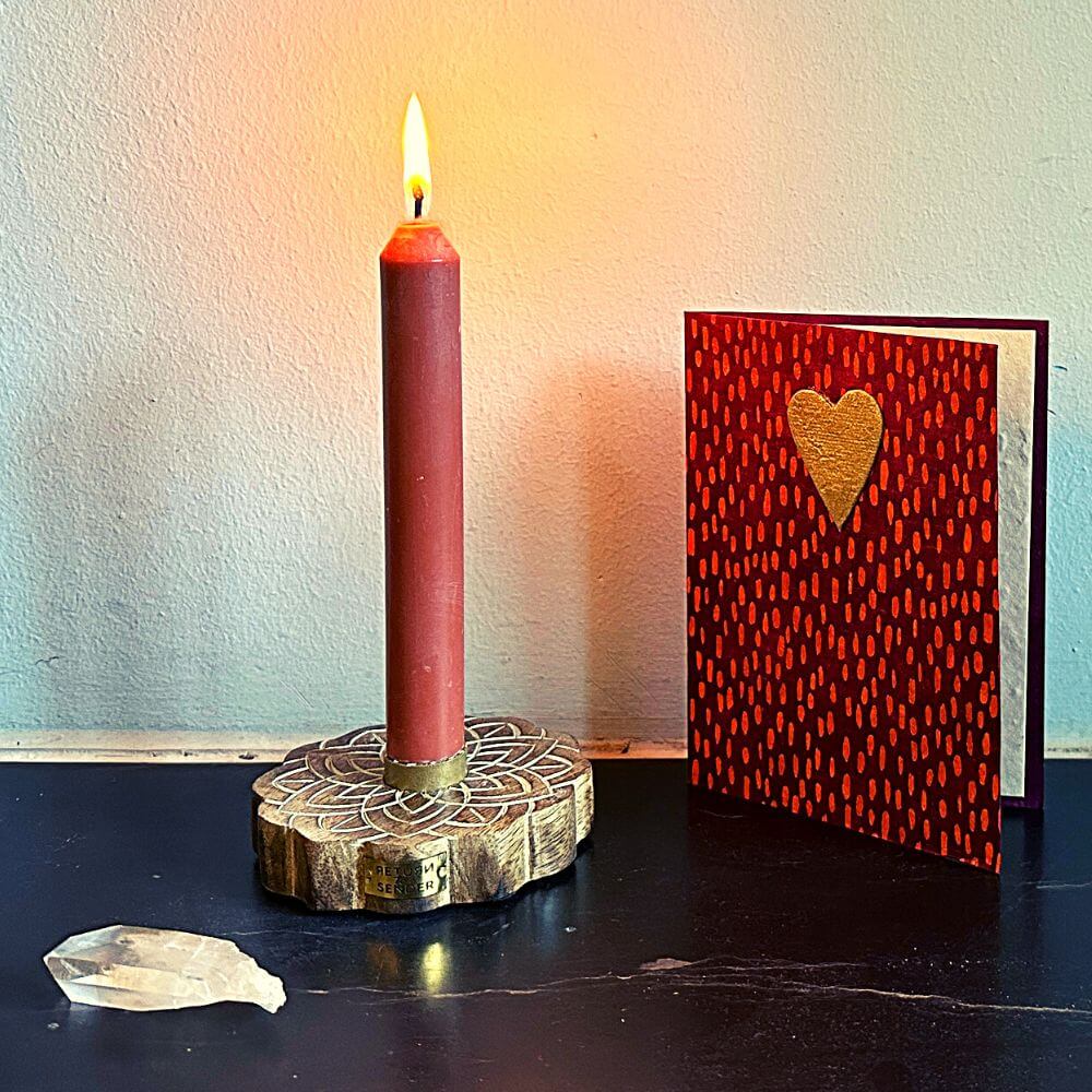 Blank houten kaartenhouder met brandend theelichtje en ecru kleurige kaart met scheprand en lieveheersbeestje van handgeschept papier.