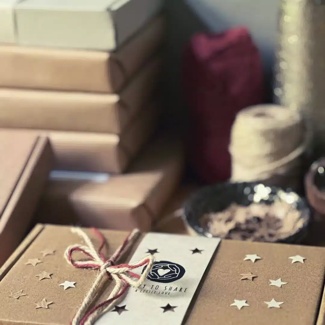 Kerstkaarten met ster en vrolijk kerstfeest in ecru en cognac kleur op een altaar doos met brandend theelichtje in aluminium kaarsenhouder.