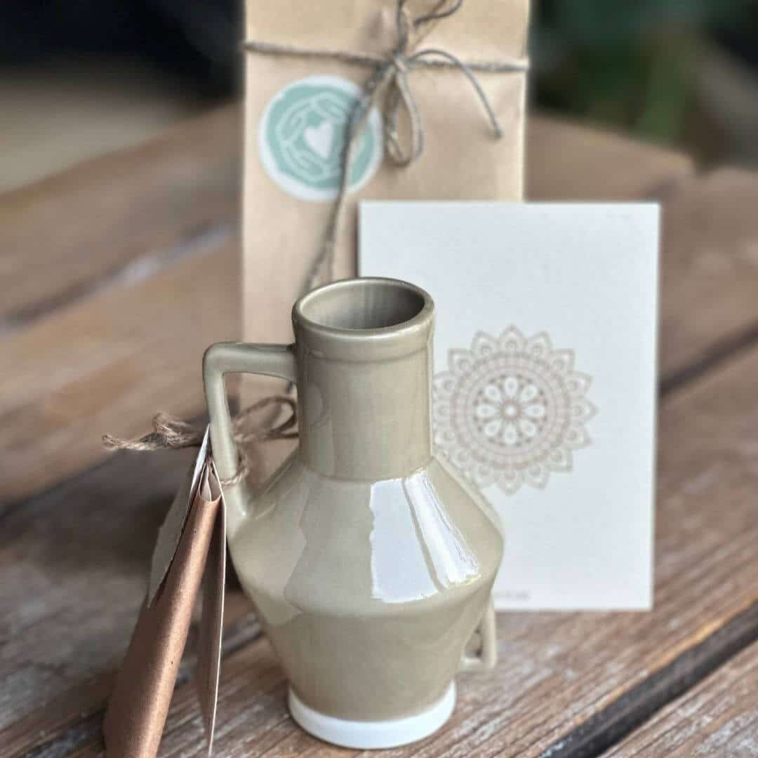 Bedrijsgeschenken-maatwerk-happy-to-share (2) Lichtzakje met levensboom, bottle vase van theezakken, keramieken schaaltje met palo santo, rozenkwarts edelsteen en mandala kaart op blank houten tafel.